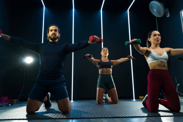 istock Three fitness coaches performing a workout routine for an online course in a gym 2120492587