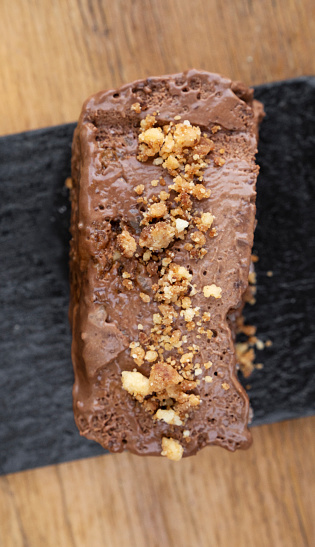 Sweet dessert. Top view of  a chocolate semifreddo with nuts in a black dish with a wooden background.