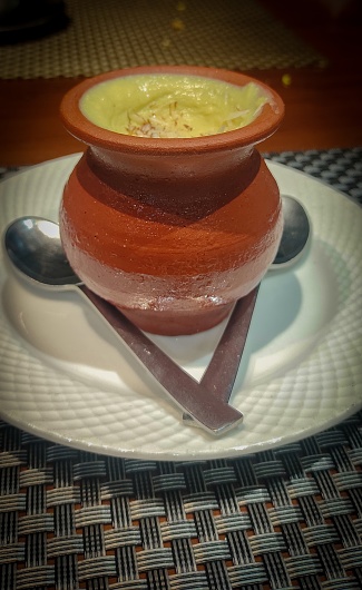 Aesthetically pleasing presentation of food served in an earthen pot on a textured table mat, highlighting an amalgamation of rustic charm and culinary artistry.
