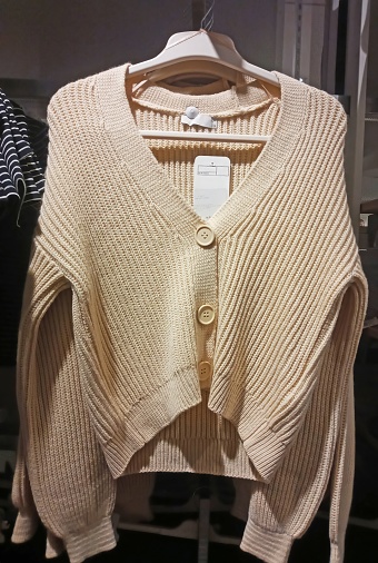 beige jacket with buttons hanging on a hanger in a supermarket