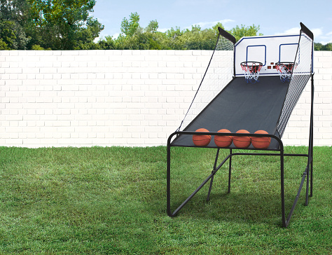 Basketball Shootout Arcade Game with Balls in backyard with green grass and brick fence