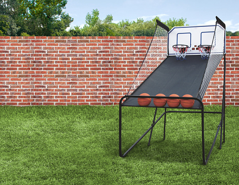Basketball Shootout Arcade Game with Balls in backyard with green grass and brick fence