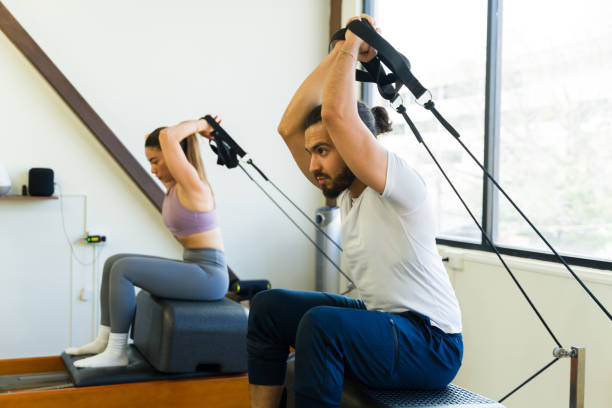 istock Two people engaging in a pilates workout using a reformer bed in a bright studio setting 2120570058
