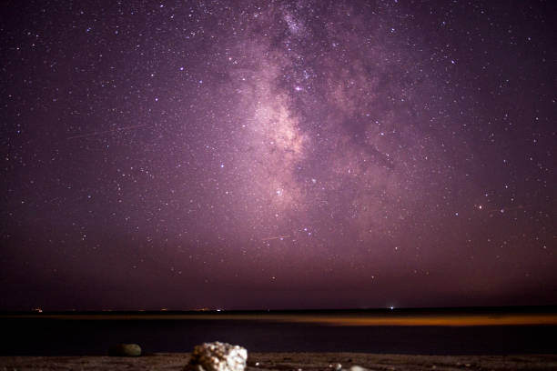 A breathtaking coastal scene as the Milky Way adorns the night sky over the sea and mountain, creating a serene and cosmic marvel.