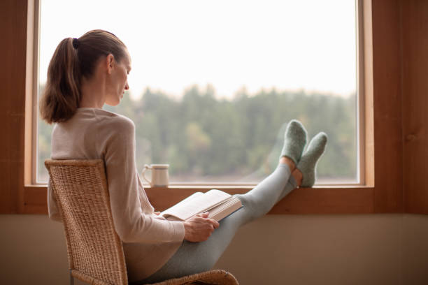 istock Woman reading a book at home 2120605735