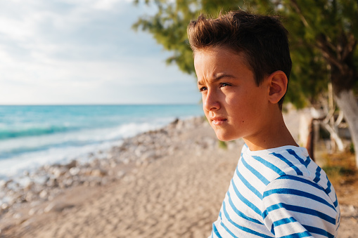 Boy standing at the beach and looking at the view