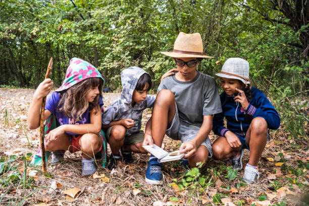 An elementary school girl of Filipino ethnicity is outdoors with her class exploring nature. She is busy writing on her notepad while walking with the group.