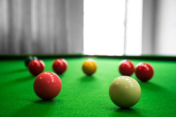A collection of snooker balls on a table beside an open window