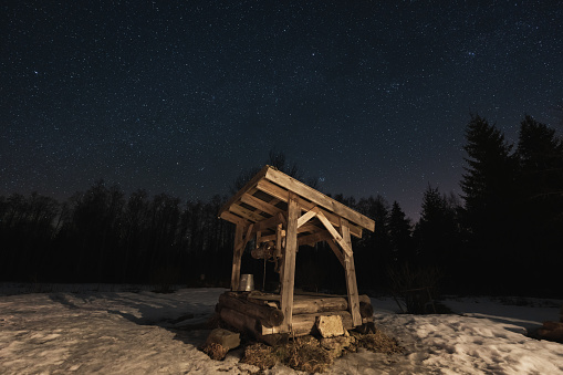 Night scene, landscape astrophoto, old well in the forest with a clear starry sky. High quality photo
