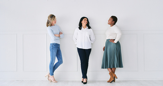 Diverse, women and happy as coworker in white background with funny conversation, bonding and together. People, colleagues and smile on work break with friendship, startup business and partnership