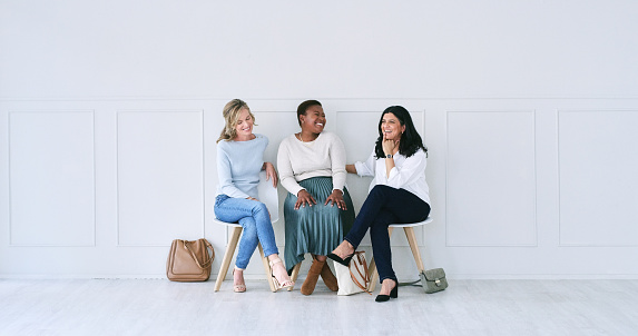 Interview, group and women in waiting room with chat, talking and business connection at recruitment agency. Networking, friends and people with diversity, happy conversation and job search together.