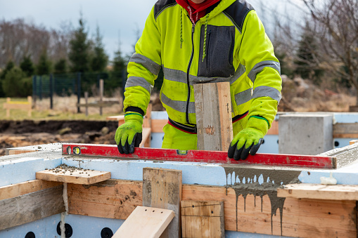 Construction Worker Using Level on Insulated Concrete Forms at Building Site