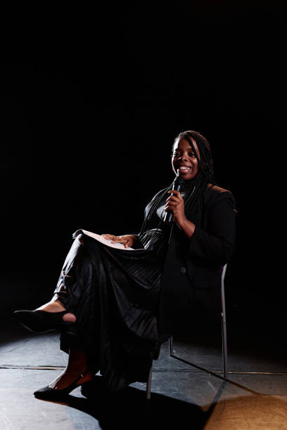 istock Smiling Woman Speaking to Microphone on Stage 2120720417
