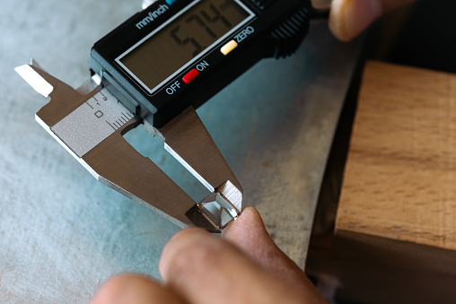 Jeweller is measuring gemstone with digital caliper.