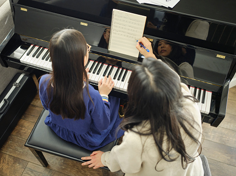A piano teacher and student having a lesson in a home.