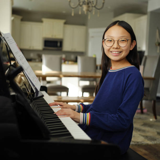 A young Korean Asian girl practicing piano in a home.