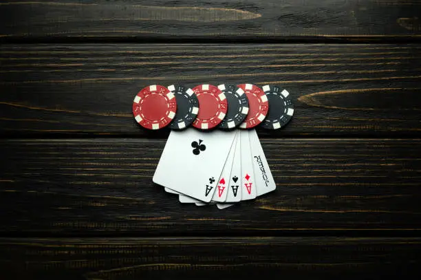 Photo of Gambling and popular poker game with a combination of flush or five aces. Chips and cards on a dark vintage table in a poker club