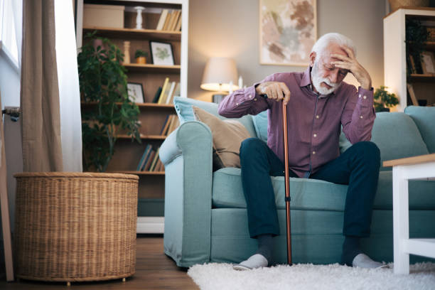 istock Senior man sitting on the sofa trying to get up 2120752037