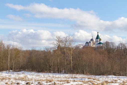 Spring landscape of town Klin with field in snow, blue sky and orthodox Resurrection church, Moscow region, Russia