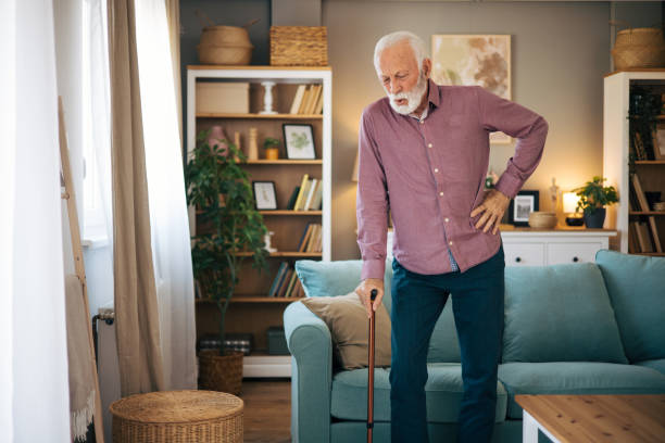 Senior man walking using walking cane Senior man with gray hair and beard slowly walking using walking cane. He is in the living room. slow walk stock pictures, royalty-free photos & images