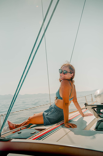 Portrait of young woman relaxing on sailboat, in summer