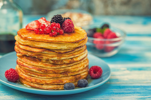Stack of homemade pancakes with berries and maple syrup