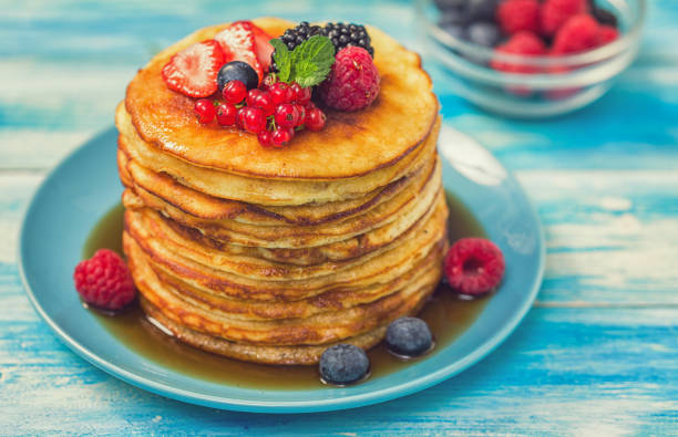 Stack of homemade pancakes with berries and maple syrup