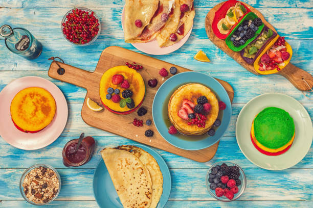 Table set up for breakfast. On the table are various pancakes and crêpes with fresh fruits.