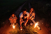 In enchanting night, a family ignites sparklers on a remote trail, basking in warm, festive light
