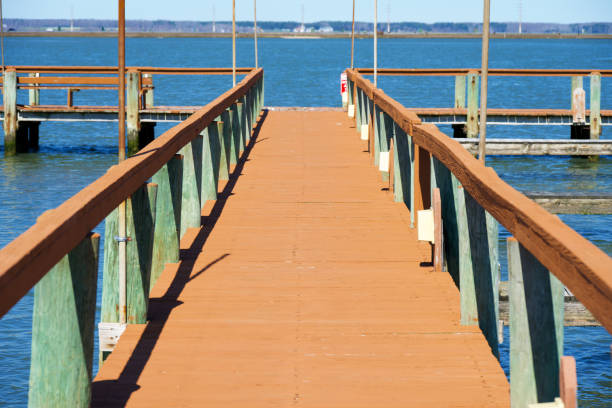 Chincoteague Island, Virginia, USA - March 21, 2024: A wooden pier juts into the Chincoteague Channel from the Chincoteague Island shoreline.