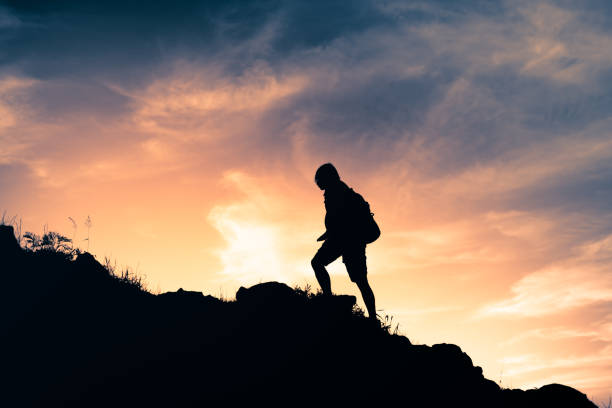 istock Man hiking up the hill at sunset. 2120847548
