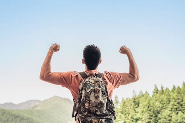 Happy strong confident man reached celebrating to reach a mountain top.