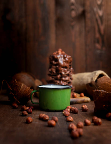 Hot chocolate in the mug with hazelnuts and stack of chocolate bars in the rustic kitchen