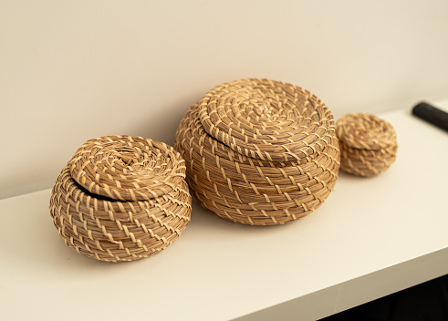 three woven straw baskets on a white shelf in the room