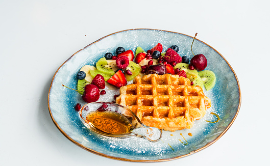 Healthy waffles with strawberries, blue berries isolated on the white background.