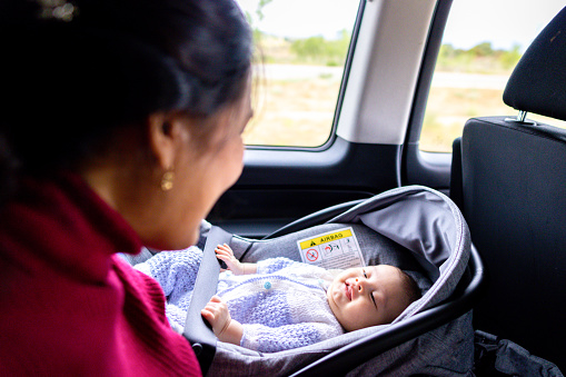 Baby looking and smiling at his mom while riding in a car