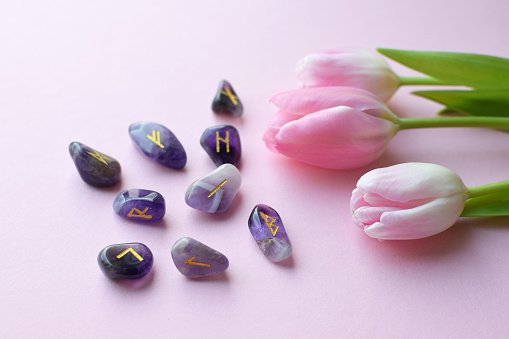 Scandinavian runes made of amethyst and a bouquet of pink tulips