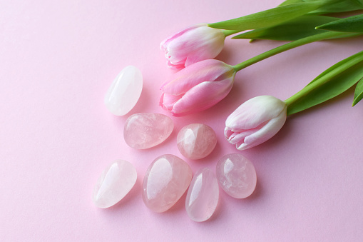 Rose quartz crystals and a bouquet of pink tulips. Healing crystals, the magic of precious stones.