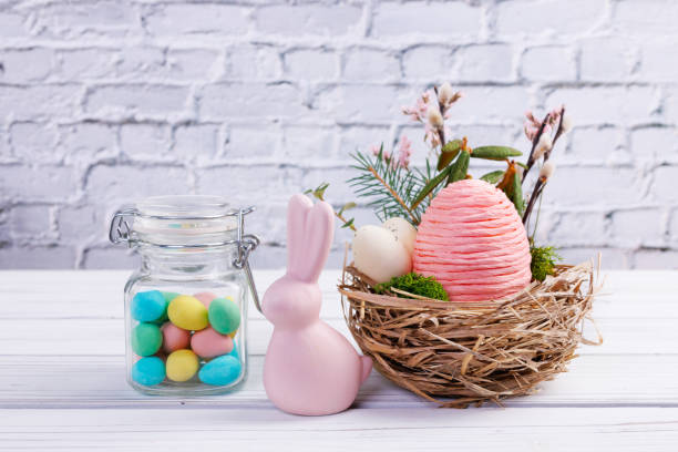 istock Easter nest with eggs and branches, bunny and jar with candies. 2121015774