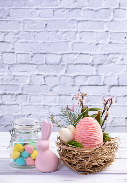istock Easter nest with eggs and branches, bunny and jar with candies. 2121016314
