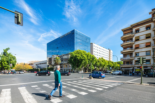 Man crossing street in Nervión with the modern Galia building in the background.