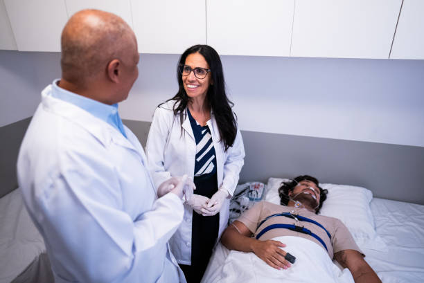 Doctors talking about patient lying at hospital bed