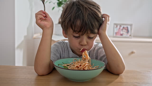 Young Boy Serving Himself A Hearty Portion Of Twirled Pasta