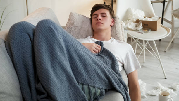istock Virus infection home man blanket napping sofa 2121102624