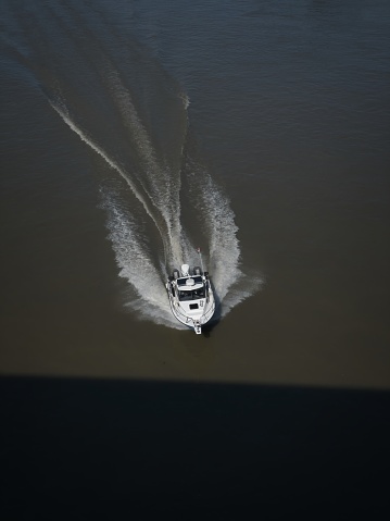 Aerial view of a boat cruising on water, creating a V-shaped wake.