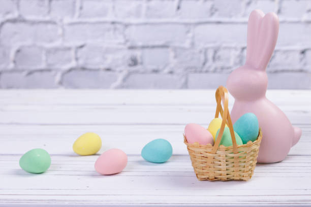 istock Easter composition with a pink rabbit figurine and a basket with candies. 2121121614