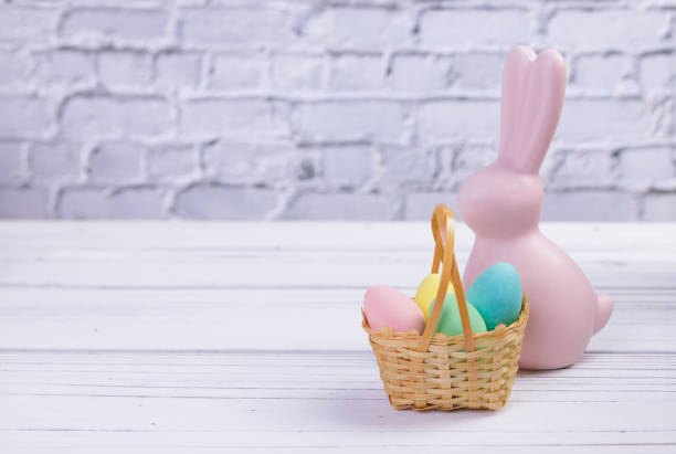 easter composition with a pink rabbit figurine and a basket with candies. - figurine easter egg easter holiday foto e immagini stock