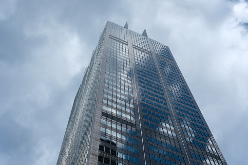 Close-up on a tall city office building with cloudy sky beyond.