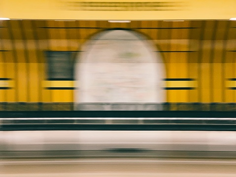 Abstract motion blur of a train speeding through a station, conveying a sense of rapid movement and urban travel.