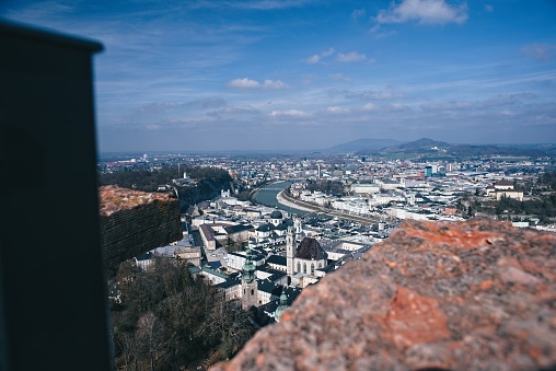 Scenic cityscape with river, viewed from high vantage point, with foreground focus on stone ledge.